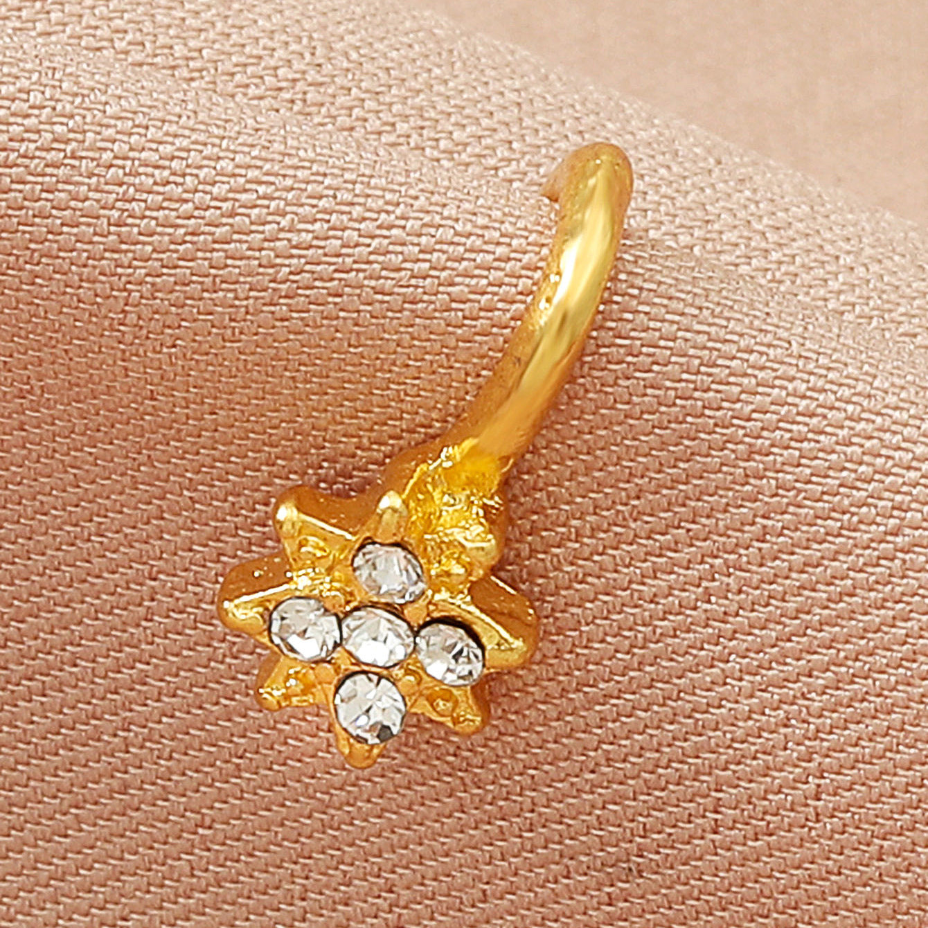 Zircon U-Shaped Leaves Heart Nose Studs with sparkling stones and gold finish against soft fabric background.